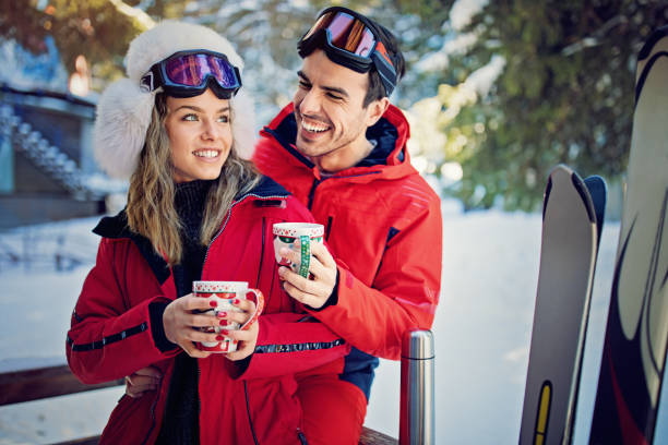 istock Young couple is hugging and drinking hot tea after skiing 911500300