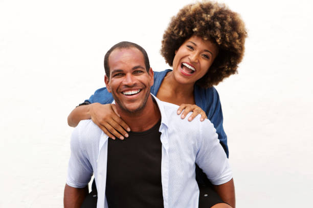 fun couple laughing in embrace by white wall