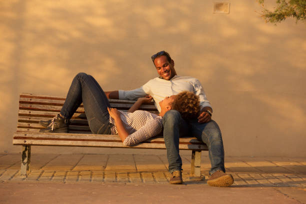 istock happy couple sitting on park bench outside 911536322