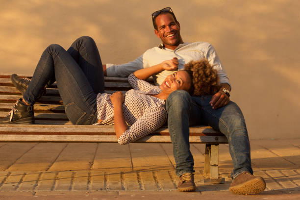 istock laughing couple sitting on park bench outside 911536324