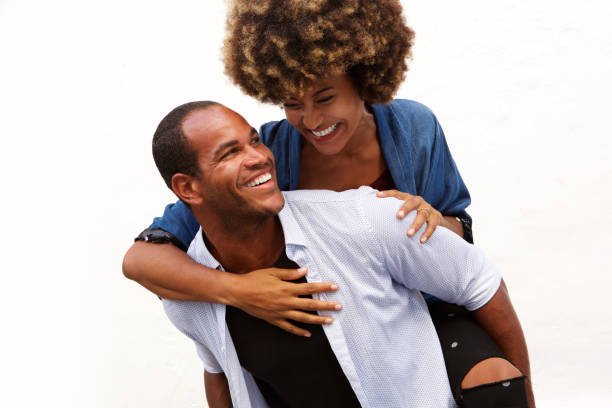 istock fun couple smiling in embrace by white wall 911536360
