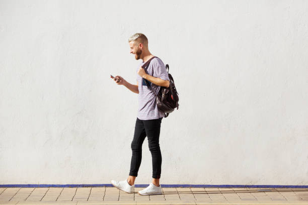 istock Full length handsome young man walking with cell phone 911537970