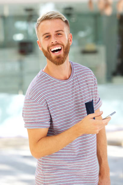 istock happy young man with beard holding cellphone 911538100