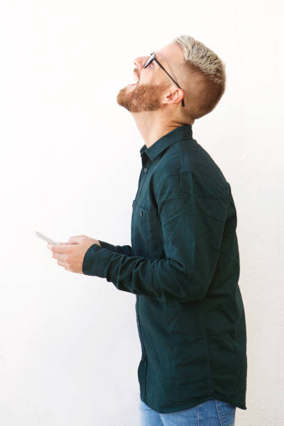 istock young guy laughing and holding cell phone against isolated white background 911538114