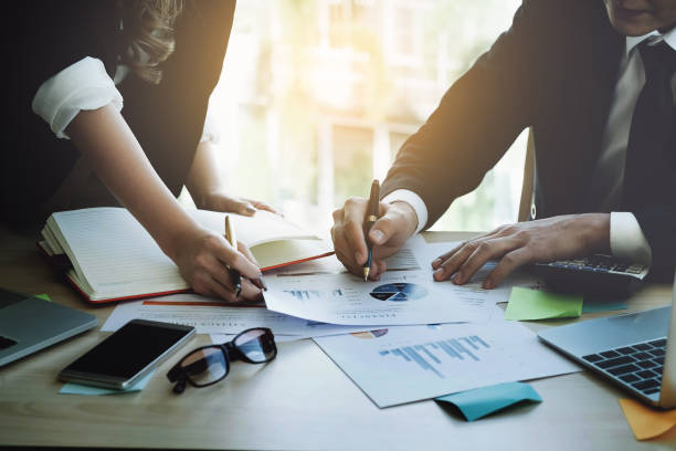 istock Businessman using pen and businesswoman using notebook with stock and cryptocurrency computer laptop with Explains Trade shares. To profit from crytocurrency in 2018. 911555396