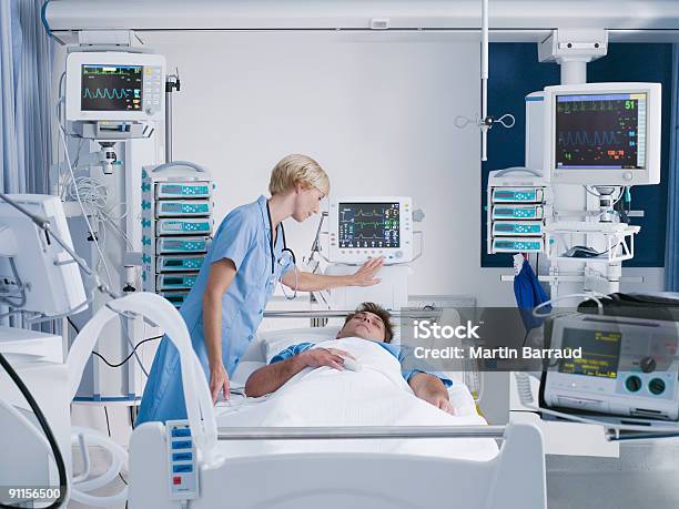 Nurse Tending Patient In Intensive Care Stock Photo - Download Image Now - Intensive Care Unit, Hospital, Patient