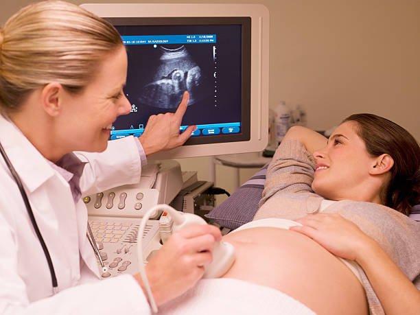 woman looking at ultrasound results with doctor - doğum öncesi bakımı stok fotoğraflar ve resimler
