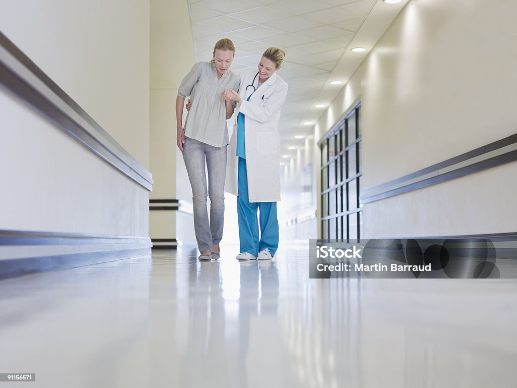 Médecin à aider un patient faible marcher dans le couloir - Photo de Patient libre de droits