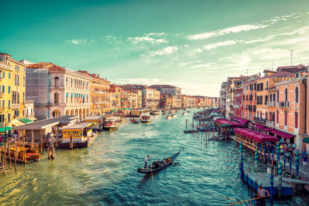View of Venice's Grand Canal A gondolier paddles towards the sunset in Venice's Grand Canal. Photo taken from the famous Rialto Bridge gondola stock pictures, royalty-free photos & images