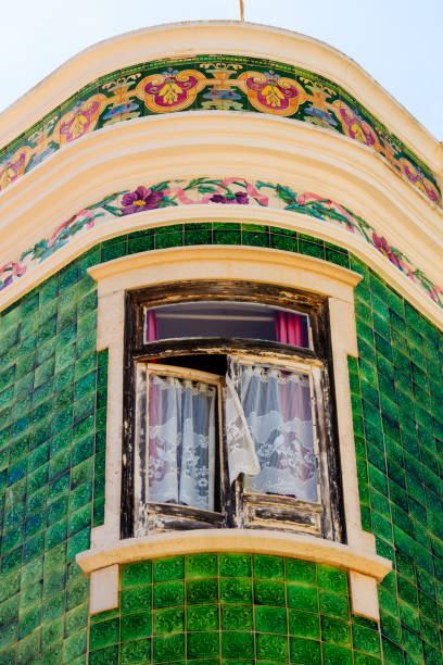 Mediterranean house facade with green tiles and white windows.