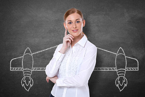 Successful businesswoman with aircraft wings drawing on blackboard