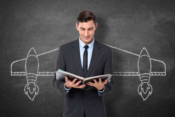 istock Businessman holding diary in front blackboard 911578890