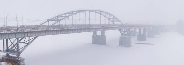 istock A large metal bridge over the river in a winter snowstorm. 911585556