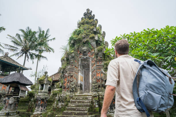 istock Young man contemplating ancient temple in Bali, Indonesia 911586608