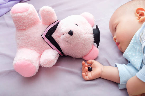 oko misia zostało odłączone przez malucha i śpiącego 10-miesięcznego dziecka, uważaj na ryzyko zadławienia dla koncepcji dzieci - behavior teddy bear doll old zdjęcia i obrazy z banku zdjęć