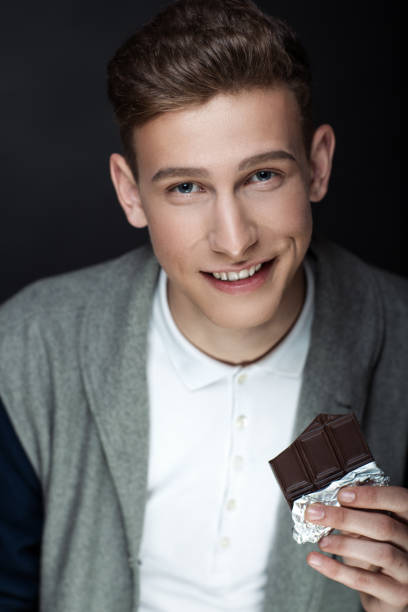 young beautiful face Stylish man close up portrait. Fashion jacket sexy bad boy. Black guy with fashionable haircut. Vertical banner conceptual idea about unhealthy food, eating chocolate candies the effects of toothache man hand holding candy bar stock pictures, royalty-free photos & images