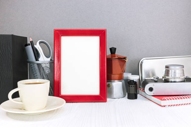 empty red photo frame with coffee pot, cup of coffee and retro camera on grey background