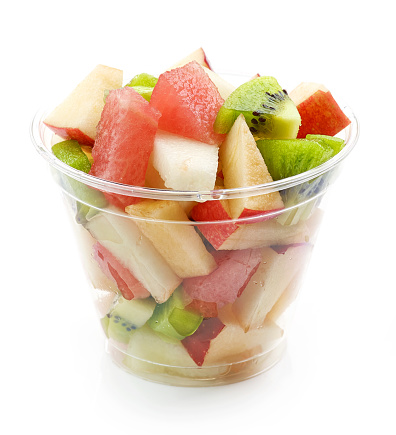 fresh fruit pieces salad in plastic glass isolated on white background