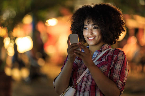 istock Smiling woman using smart phone at night on street 911619142