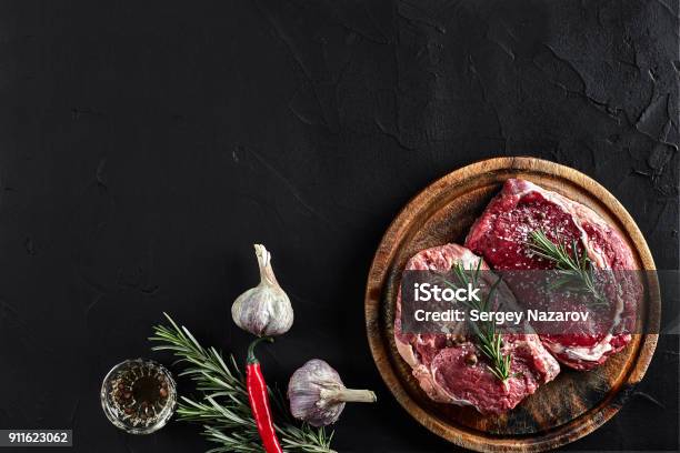 Raw Beef Steak With Spices And Ingredients For Cooking On Cutting Board And Slate Background Top View Stock Photo - Download Image Now