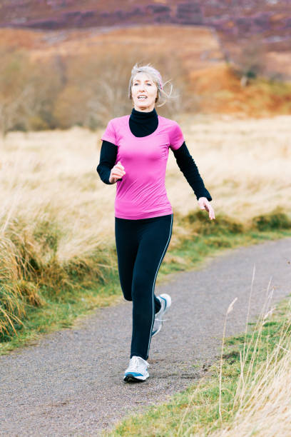 istock Senior woman jogging on outdoor trail during fall 911630218