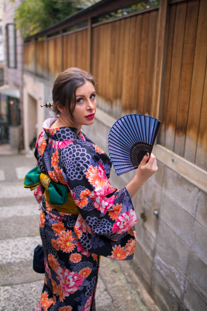 istock British woman in kimono with folding fan looking over shoulder 911636454