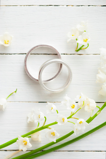 white flowers and wedding rings on bright wood table