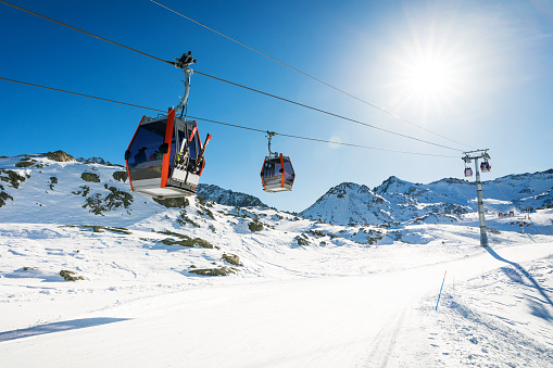 ski lift gondolas against blue sky over slope at ski resort on sunny winter day at Italy Alps