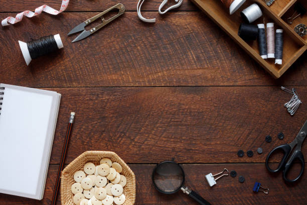 immagine aerea piatta di articoli di stilista concetto di sfondo. accessorio da cucito con vista dall'alto o attrezzatura sartoriale su moderno legno marrone rustico nello studio della scrivania dell'ufficio domestico. strumenti di creazione in officina. - sewing tailor thread sewing kit foto e immagini stock