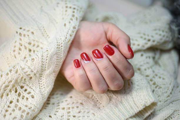 istock Hands with long artificial manicured nails colored with red nail polish 911675142