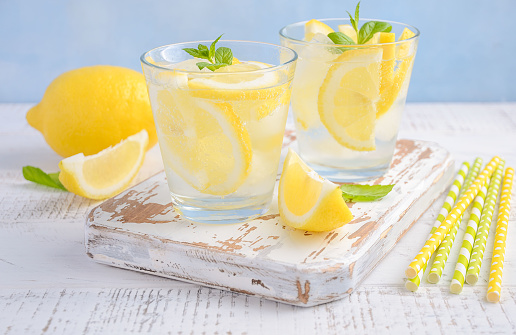 Cold refreshing summer drink with lemon and mint on wooden background, selective focus.
