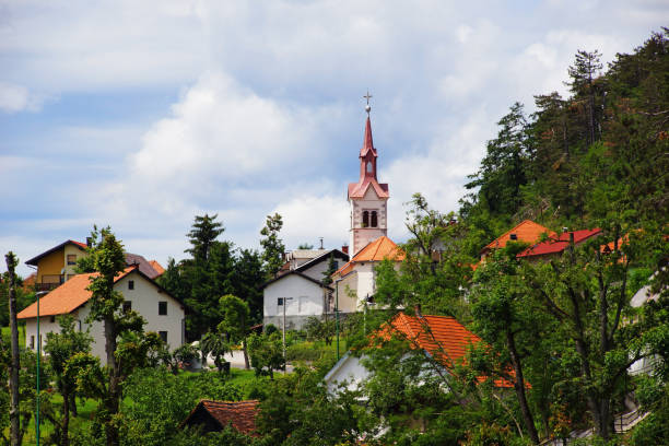 The white and red Postojna town in Slovenia hidden among green trees, on the main plan the bell tower and the church