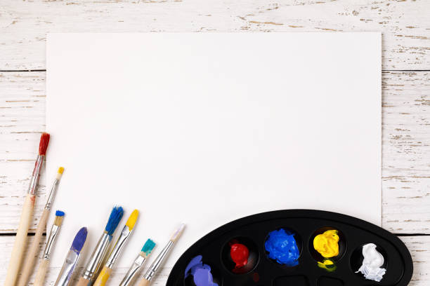 artistic accessories: a palette with paints and tassels for drawing on a wooden table with space for text - artists canvas yellow white red imagens e fotografias de stock