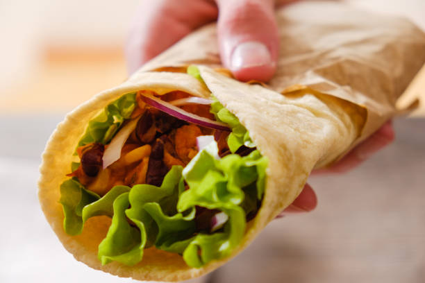 istock Mexican burrito in hand with chicken, pepper and beans 911687300