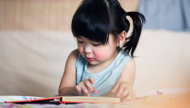 istock Charming and lovely asian kid concentrated on reading book 911687436