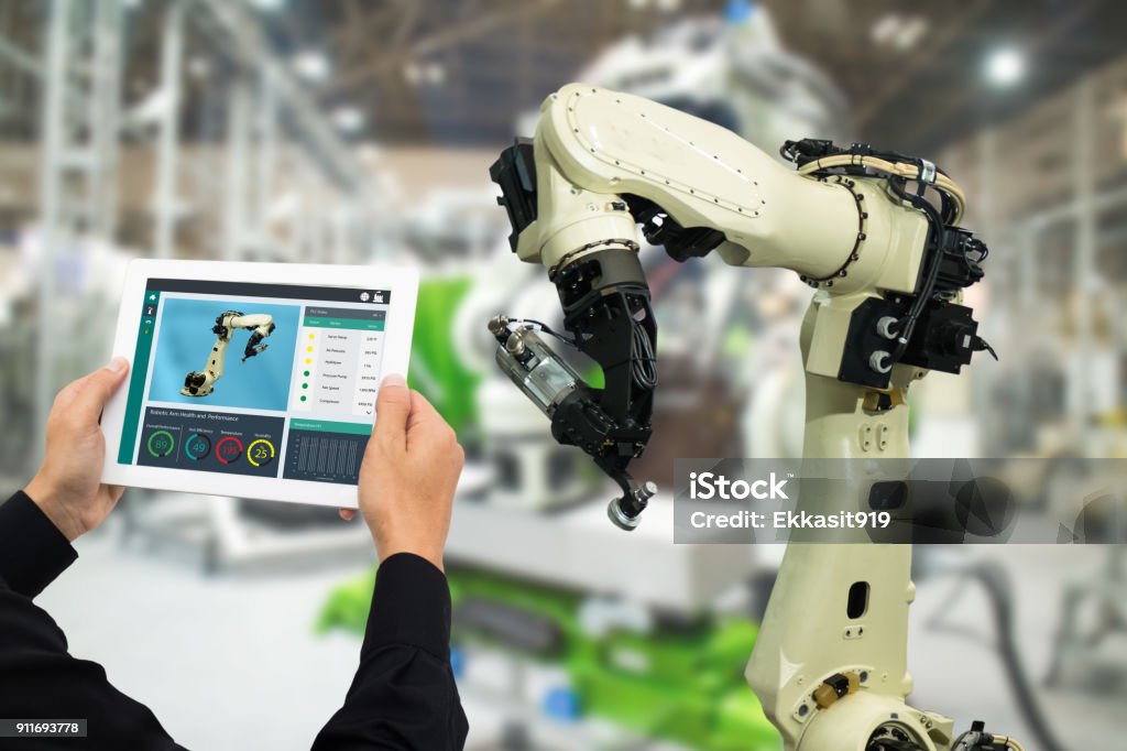 iot industria 4.0 concept,ingegnere industriale che utilizza software (realtà aumentata, virtuale) in tablet per monitorare la macchina in tempo reale. Uso intelligente in fabbrica Braccio robot automazione nella produzione automobilistica - Foto stock royalty-free di Internet delle cose