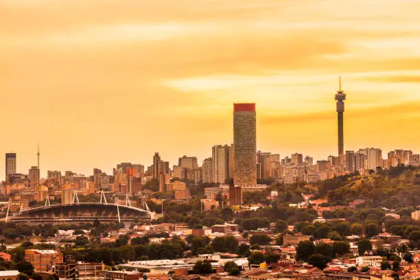 Johannesburg cityscape panorama in the late afternoon with Hillbrow residential suburb and the iconic Hillbrow communication tower and Ponte apartments. Johannesburg is one of the forty largest metropolitan cities in the world, and the world's largest city that is not situated on a river, lakeside, or coastline. It is also the source of a large-scale gold and diamond trade, due being situated in the mineral-rich Gauteng province.