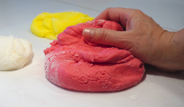istock Woman hand kneads a red dough ball 911712414