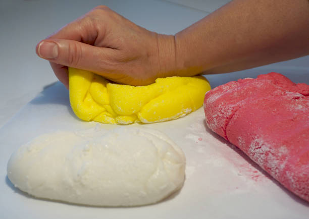 mão de mulher amassar uma massa amarela - baking cake making women - fotografias e filmes do acervo