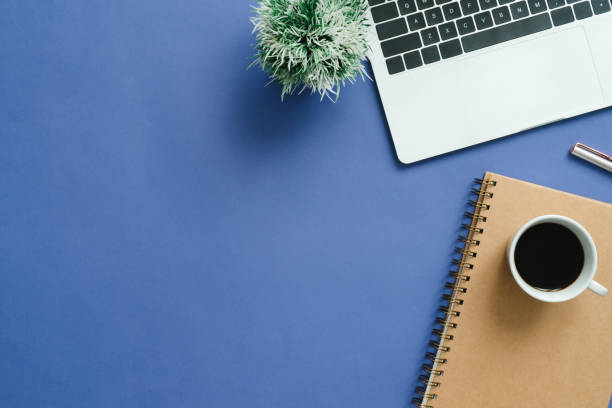 istock Minimal work space - Creative flat lay photo of workspace desk. Top view office desk with laptop, notebooks and coffee cup on blue color background. Top view with copy space, flat lay photography. 911721268