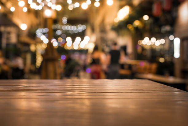 istock Wood table top with blur of lighting in night cafe restaurant background/selective focus. 911739108