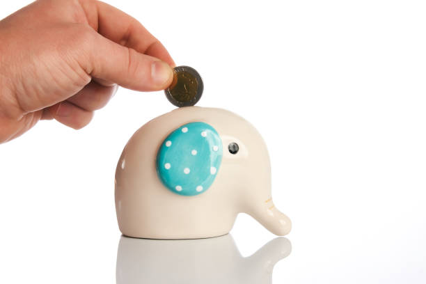 Hand drop a coin in money box elephant bank isolated on white background with copy space. Money saving concept