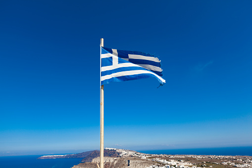 national flag of greece in the wind over santorini island, the cyclades, greece.