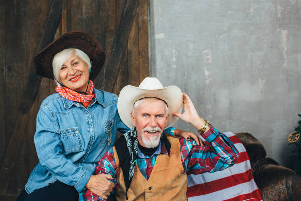 Couple in a stiff, old classic retro pose, standing in front of wooden stable.