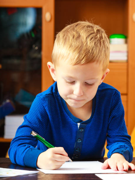 istock boy child with pen writing doing homework. At home. 911749886