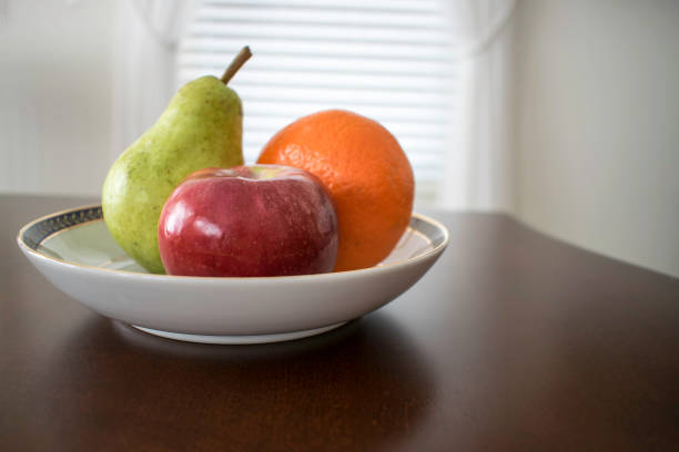 istock An apple a pear and an orange in a bowl on table 911754898
