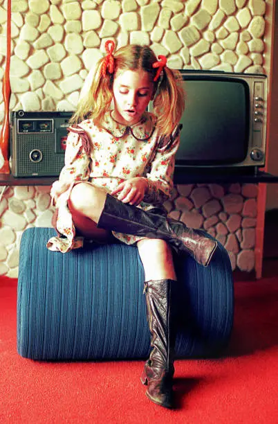 vintage  image of a girl from the seventies sitting in the living room.
