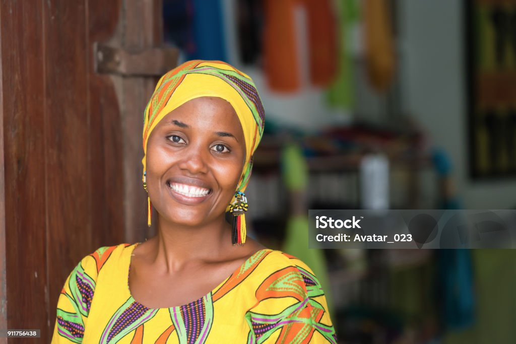 Beautiful African woman Young African woman in traditional clothes standing in entrance of her store, smiling at camera Africa Stock Photo