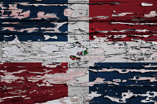 Flag of the Dominican Republic painted on a grunge wooden board.