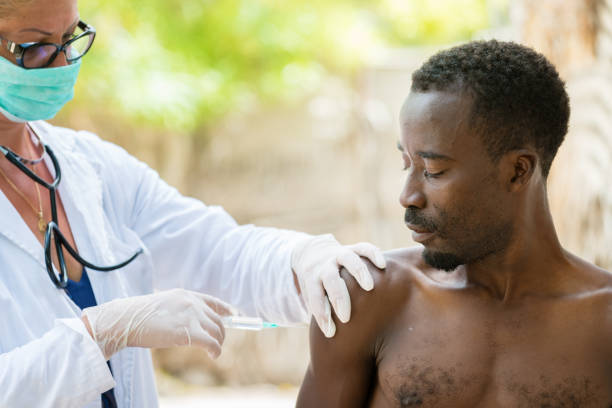 Vaccination in Africa Vaccination of African black man outdoors.Female Caucasian doctor with a medical mask on her face ebola stock pictures, royalty-free photos & images